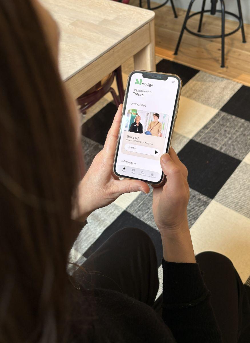 kvinna håller mobil och använder Modigo-appen